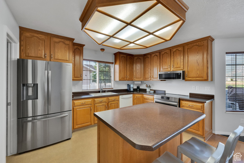 Kitchen with stainless steel appliances, dark countertops, brown cabinetry, and a kitchen breakfast bar