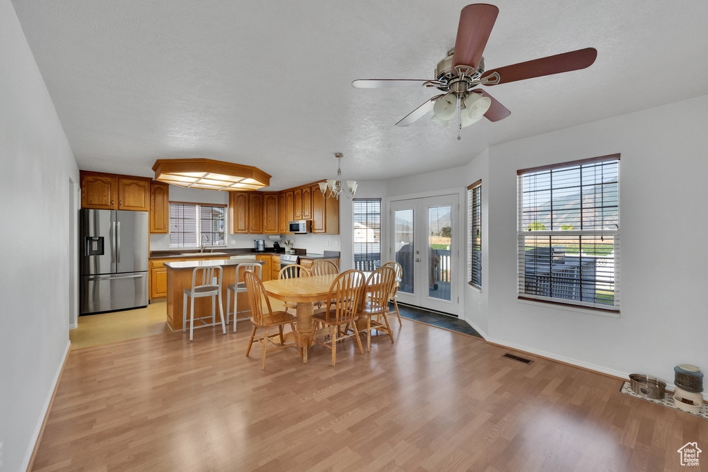 Dining room featuring light wood-style floors, a ceiling fan, and a chandelier