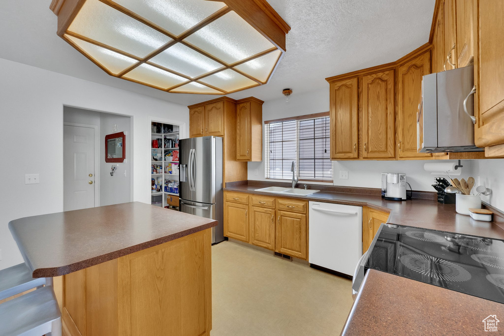 Kitchen featuring white dishwasher, stainless steel fridge with ice dispenser, dark countertops, a center island, and a textured ceiling