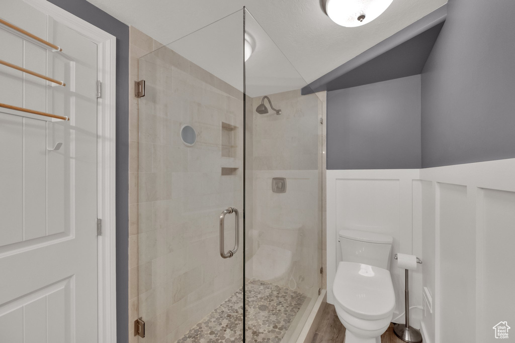 Bathroom with a shower stall, wainscoting, and wood finished floors