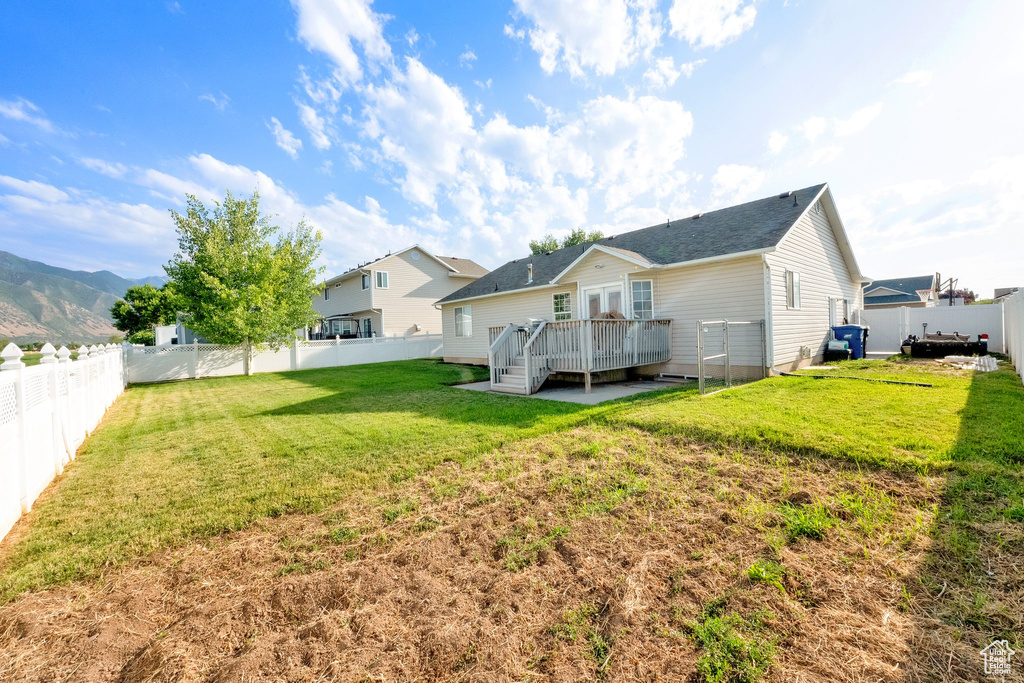 Back of property with a deck, a fenced backyard, and a shingled roof