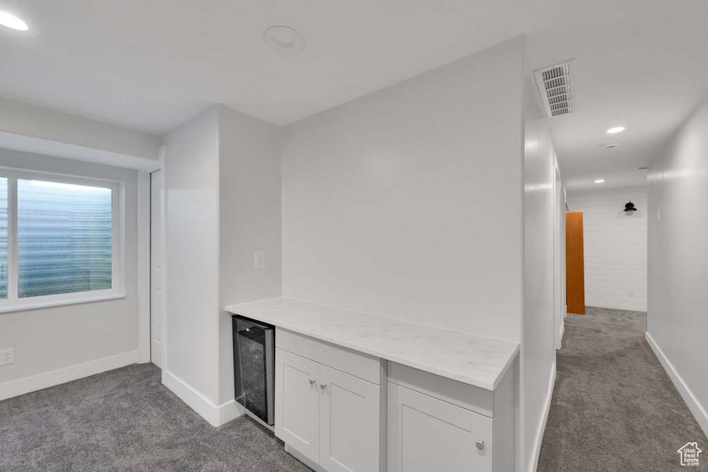Hallway with beverage cooler, dark carpet, and recessed lighting