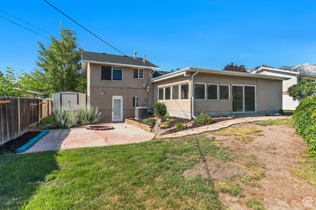 Rear view of house with a fire pit, a patio area, stucco siding, and a storage shed