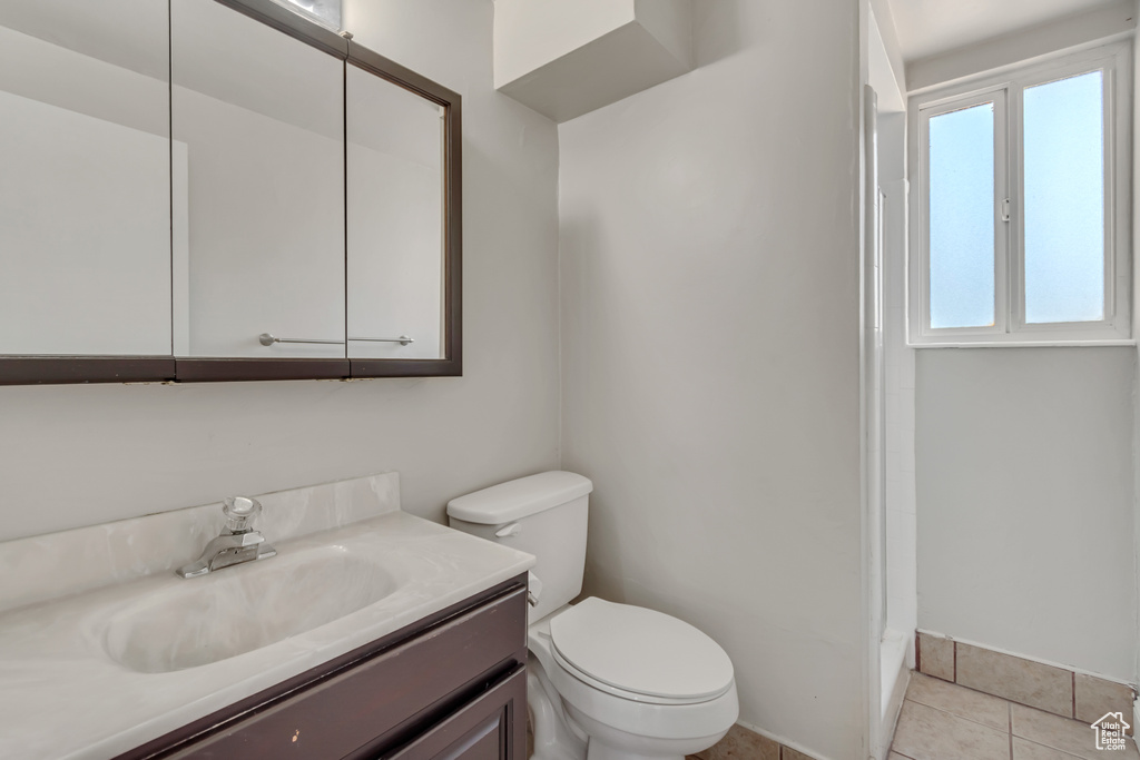 Bathroom with vanity, a shower, and tile patterned floors
