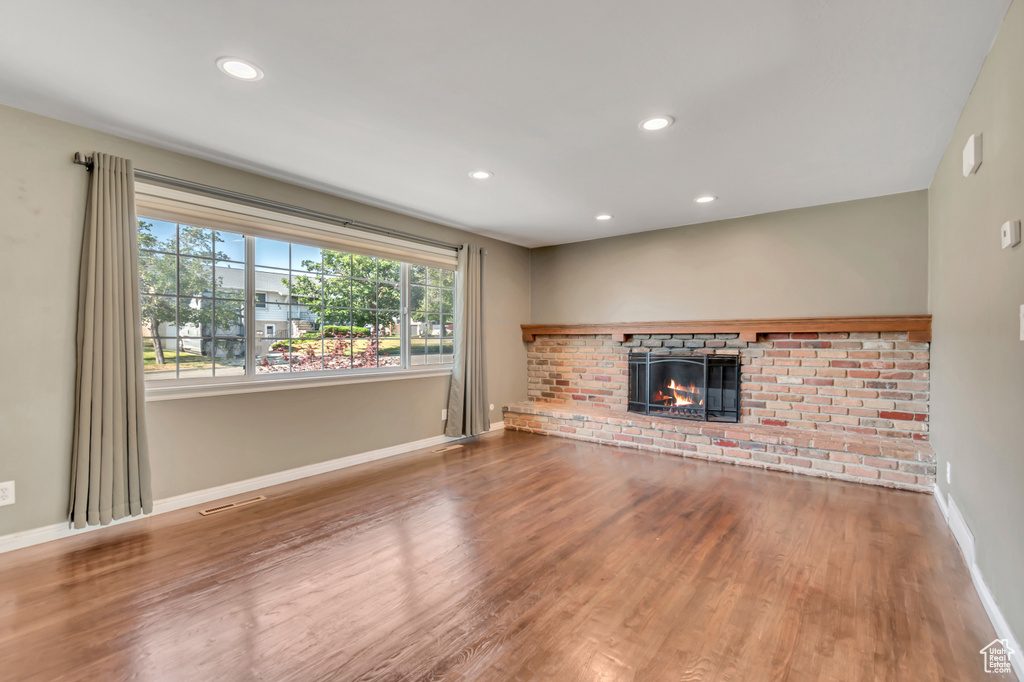 Unfurnished living room with wood finished floors, recessed lighting, and a fireplace