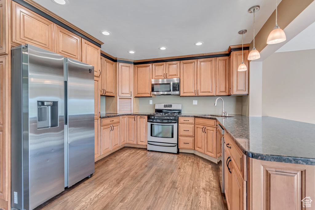 Kitchen featuring appliances with stainless steel finishes, light brown cabinetry, light wood-style floors, recessed lighting, and a peninsula