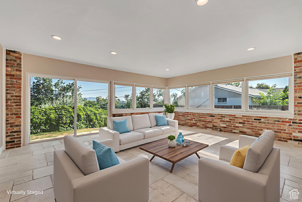 Sunroom featuring stone tile flooring, recessed lighting, and brick wall