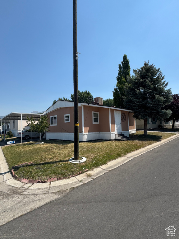 Manufactured / mobile home with entry steps, a carport, and a front lawn