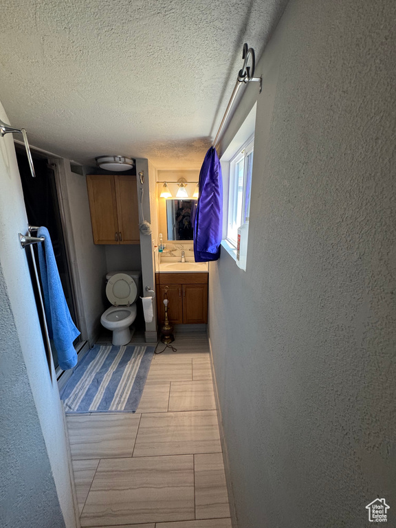 Bathroom featuring a textured wall, vanity, and a textured ceiling