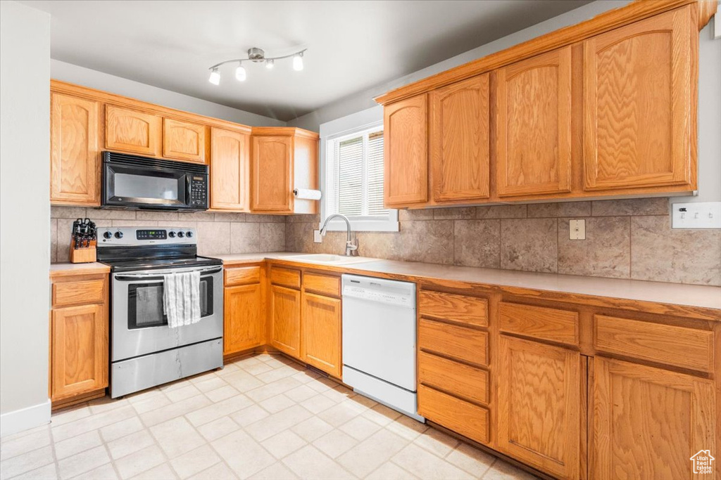 Kitchen featuring stainless steel range with electric stovetop, black microwave, white dishwasher, light countertops, and tasteful backsplash