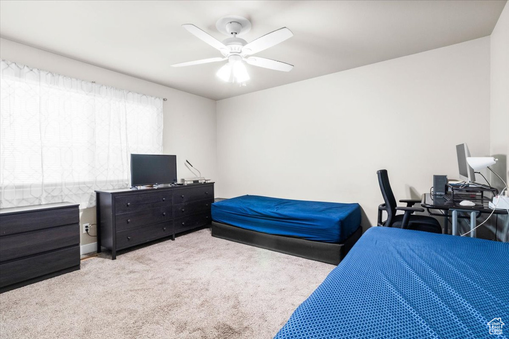 Bedroom with light colored carpet and a ceiling fan