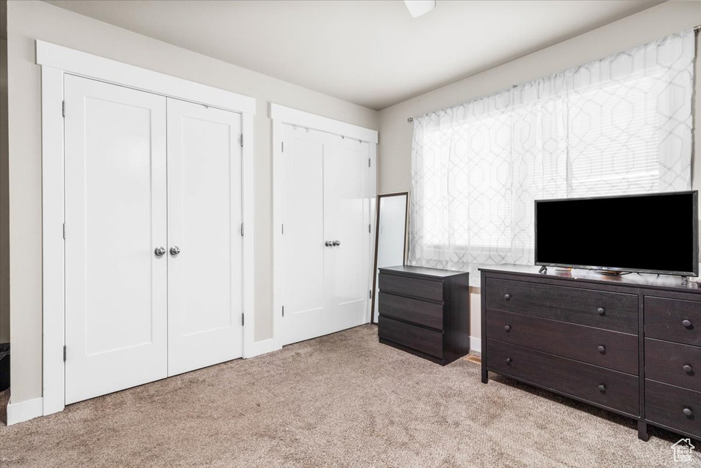 Bedroom featuring light carpet and two closets