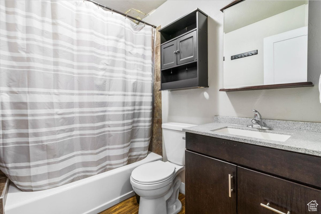 Full bath with shower / bath combo, vanity, and wood finished floors