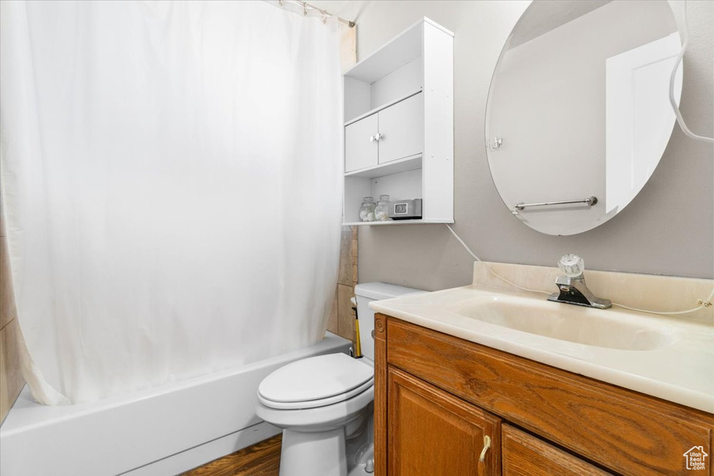 Full bath with vanity, shower / tub combo, and wood finished floors