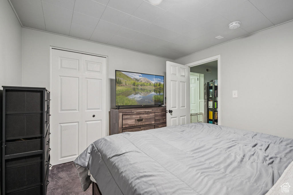 Bedroom with dark colored carpet and a closet