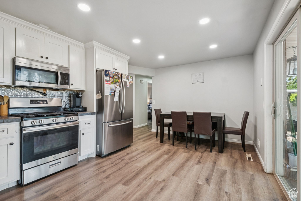 Kitchen featuring stainless steel appliances, dark countertops, light wood-type flooring, recessed lighting, and white cabinets