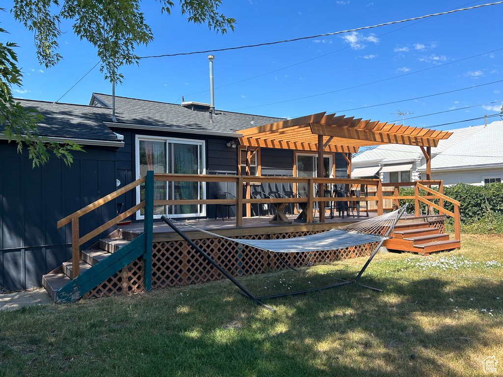 Back of property with a pergola, a shingled roof, a lawn, and a wooden deck