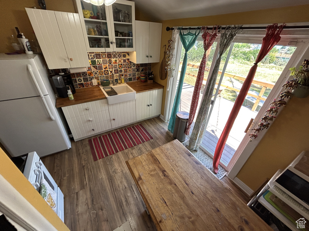 Kitchen with freestanding refrigerator, butcher block countertops, wood finished floors, and backsplash