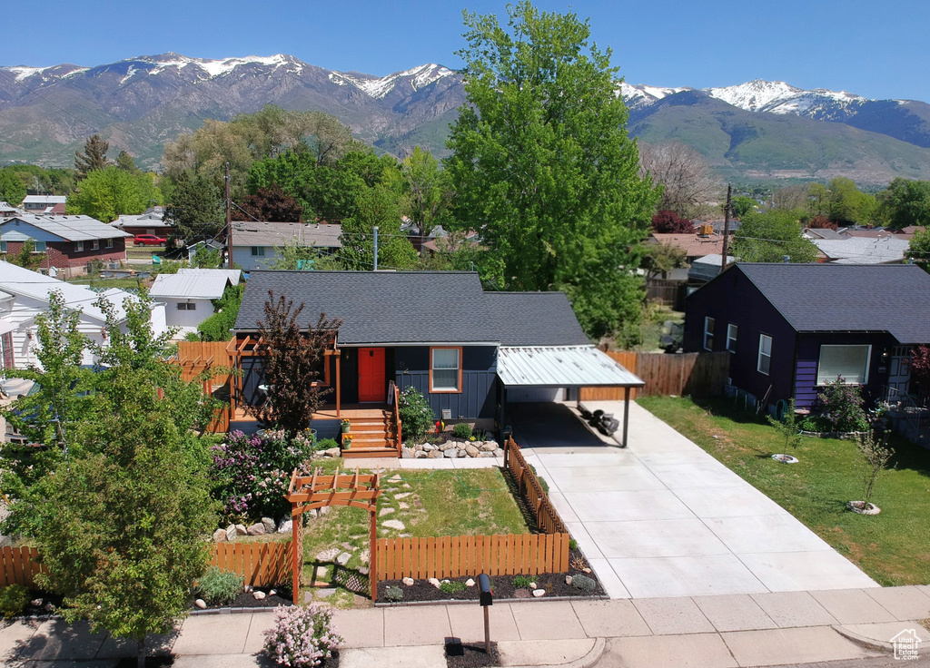 View of front facade with a mountain view, driveway, a residential view, and roof with shingles