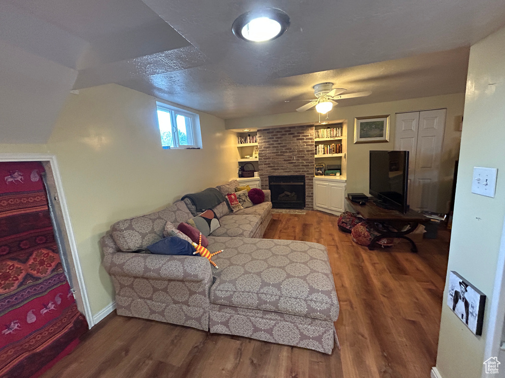 Living room featuring wood finished floors, a ceiling fan, and a fireplace