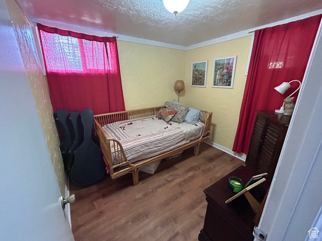 Bedroom with a textured ceiling and wood finished floors