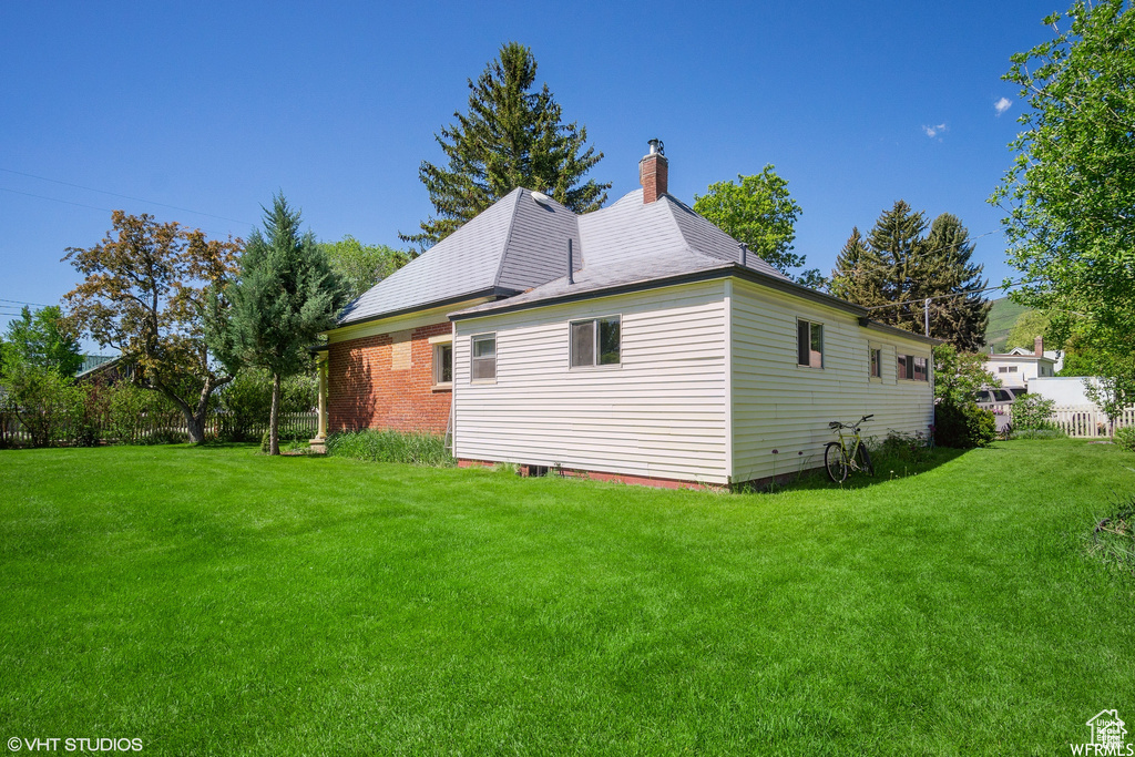 View of property exterior featuring a lawn and a chimney