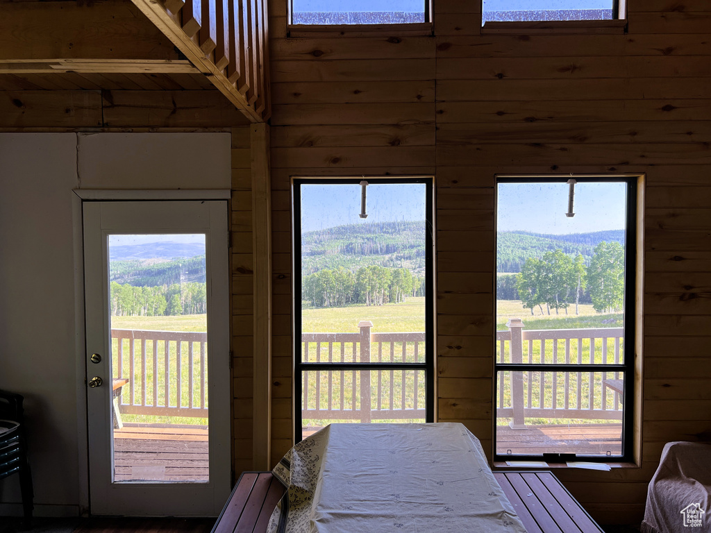 Bedroom featuring wooden walls, access to outside, a high ceiling, and multiple windows