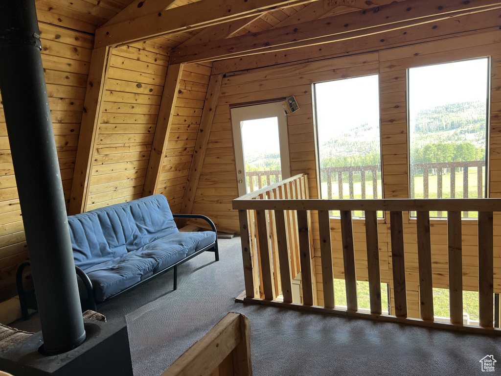 Living area featuring lofted ceiling, carpet floors, and wood walls