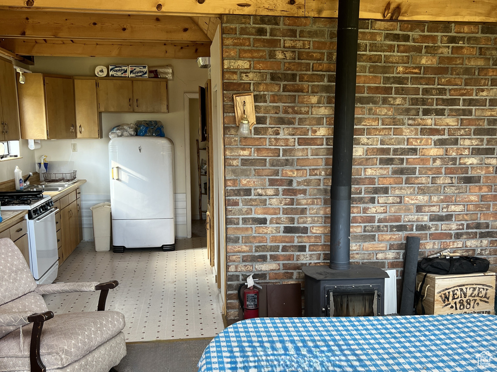 Dining room with a wood ceiling with exposed beams, a wood stove, and brick wall