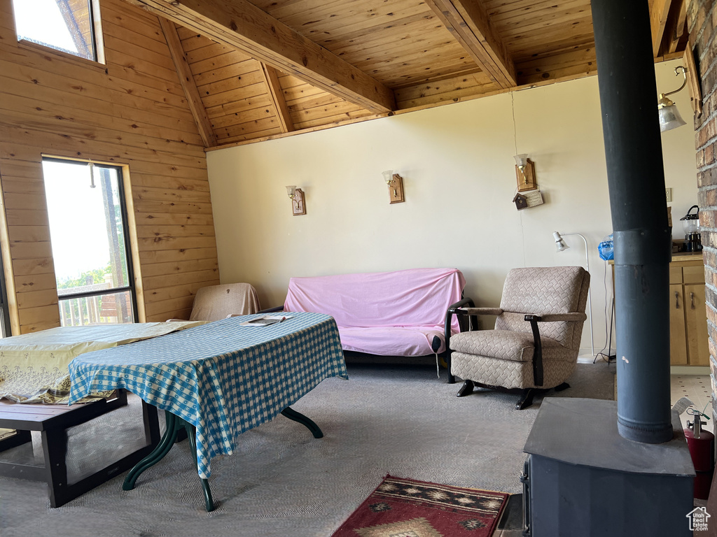 Carpeted bedroom with a wood stove, wood ceiling, and wood walls