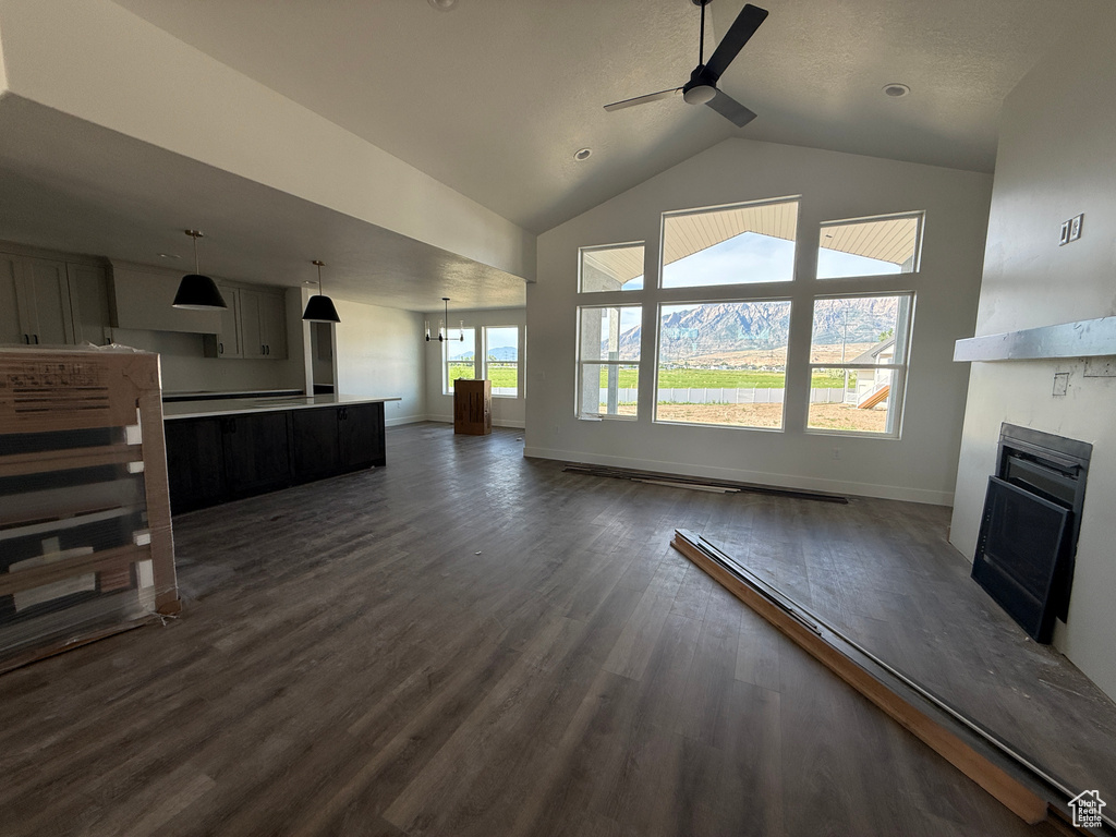 Unfurnished living room with ceiling fan, a fireplace, dark wood-style flooring, and high vaulted ceiling