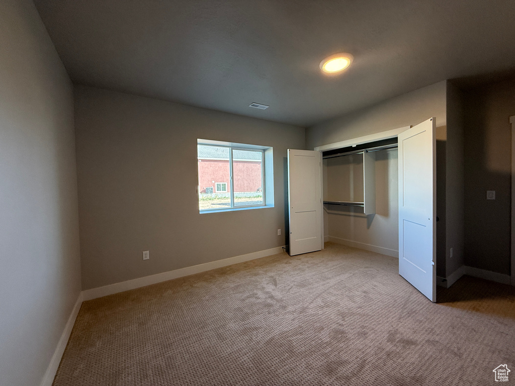 Unfurnished bedroom with light colored carpet and a closet