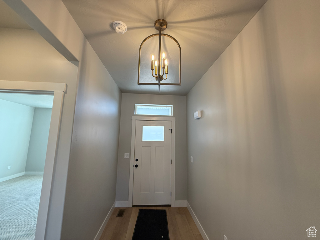 Doorway with a chandelier and wood finished floors