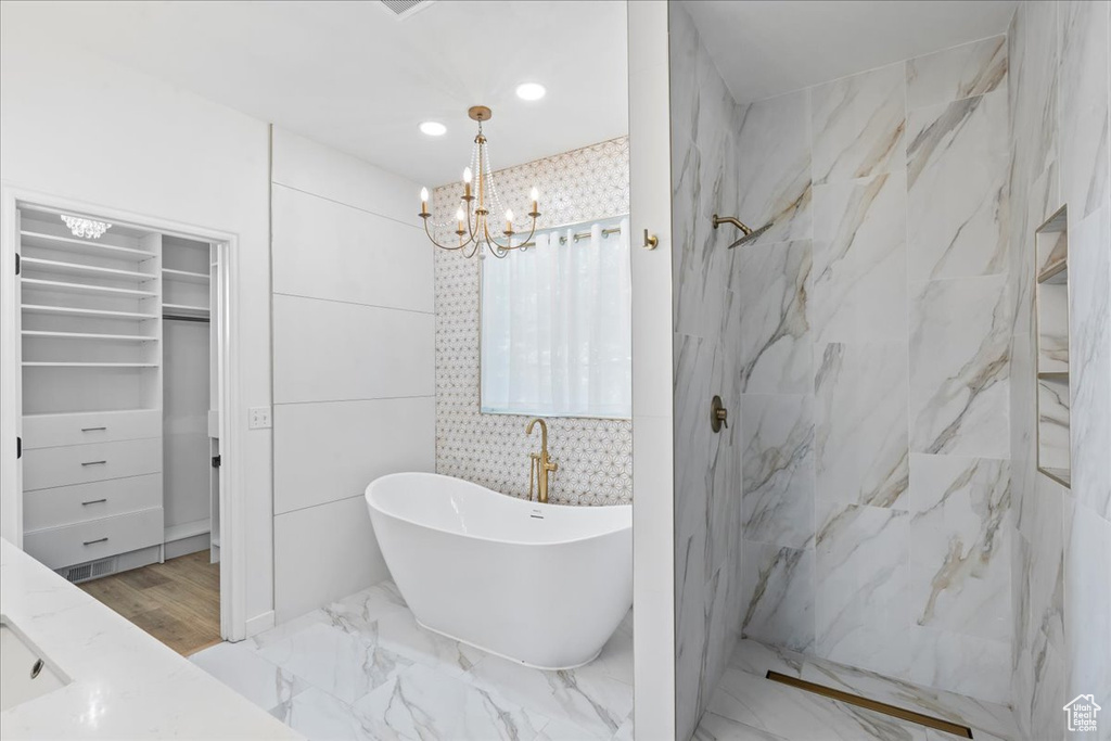 Full bathroom with a freestanding bath, a spacious closet, a chandelier, a marble finish shower, and marble finish floors