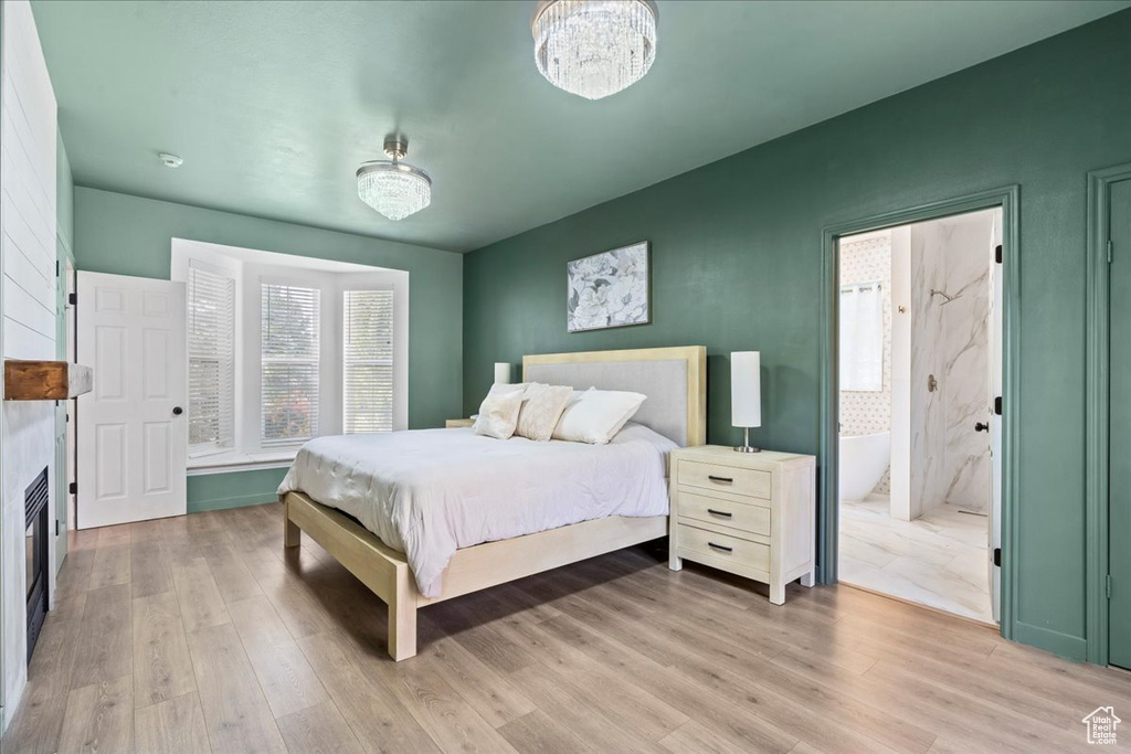 Bedroom featuring light wood finished floors, a fireplace, and a chandelier