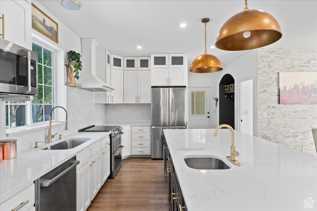 Kitchen with stainless steel appliances, premium range hood, white cabinetry, dark wood-style flooring, and recessed lighting