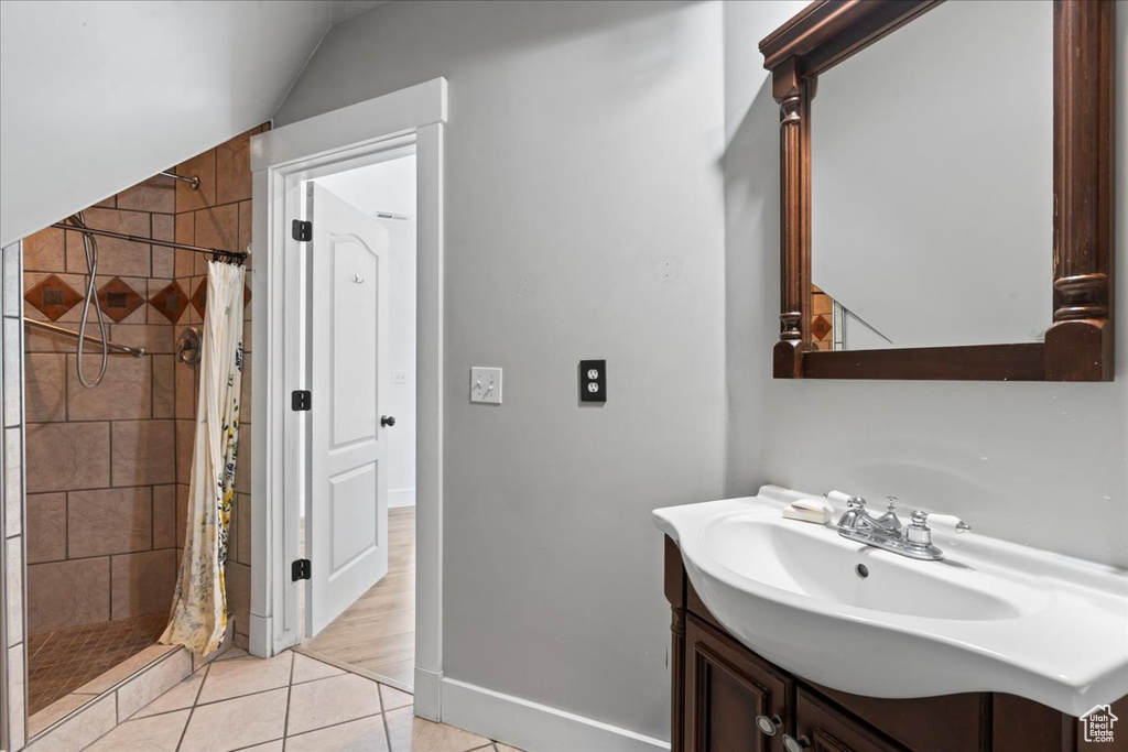 Full bath with vanity, a stall shower, tile patterned floors, and vaulted ceiling