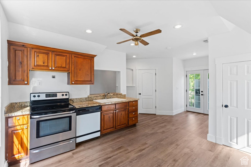 Kitchen with electric stove, dishwasher, ceiling fan, brown cabinetry, and recessed lighting