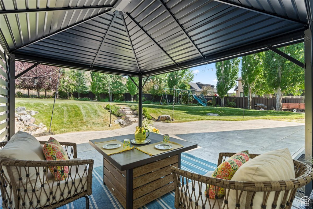 Fenced backyard featuring a playground, a patio, and an outdoor hangout area