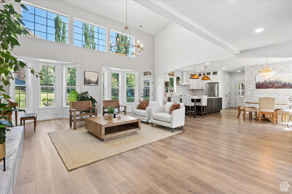 Living area featuring a chandelier, a high ceiling, and light wood-style floors