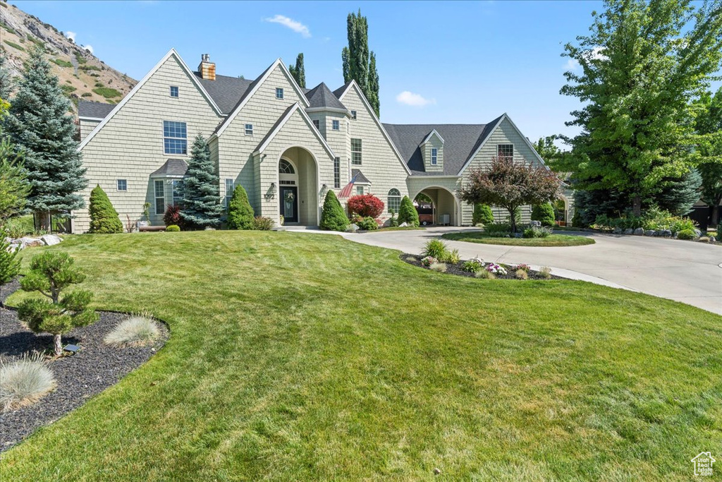 View of front of home featuring a front lawn, a chimney, and curved driveway