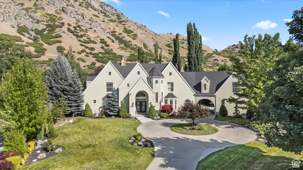 Shingle-style home featuring curved driveway, a mountain view, french doors, a chimney, and a front lawn