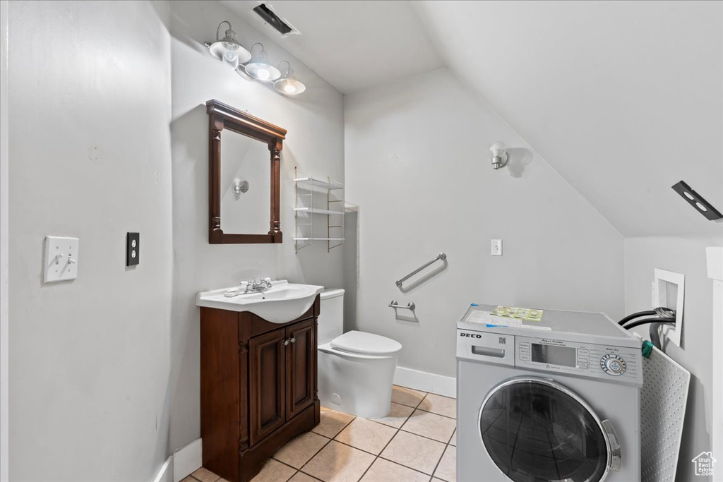 Bathroom featuring washer / dryer, vanity, vaulted ceiling, and tile patterned flooring