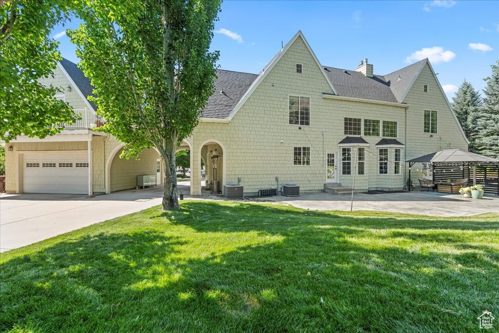 Back of house featuring entry steps, roof with shingles, a yard, and concrete driveway