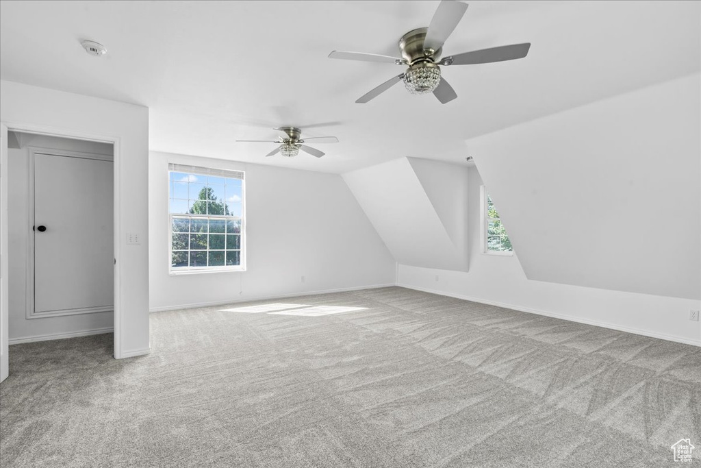 Additional living space with carpet flooring, healthy amount of natural light, a ceiling fan, and vaulted ceiling