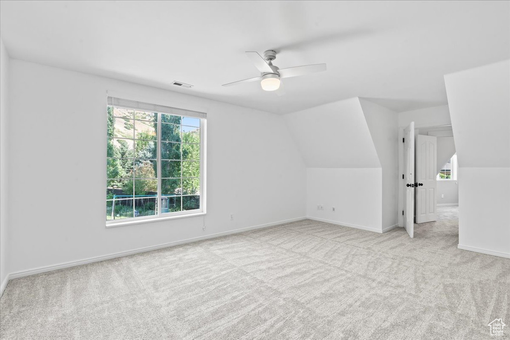 Additional living space with carpet flooring, plenty of natural light, ceiling fan, and lofted ceiling