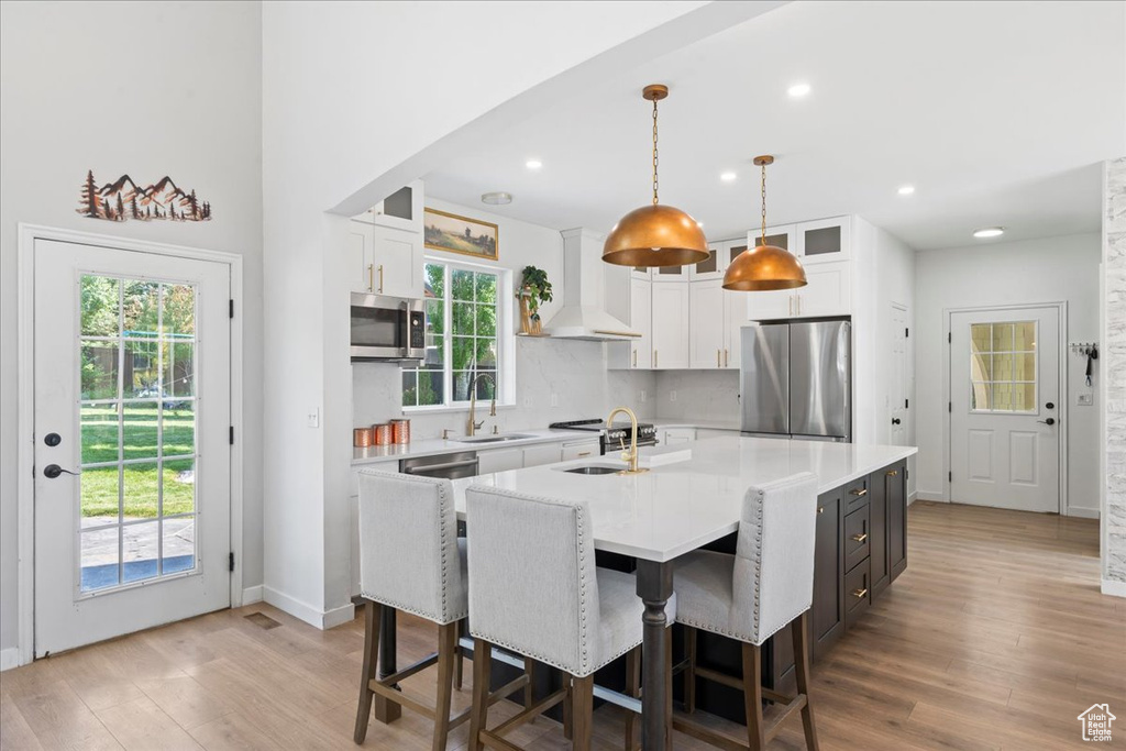 Kitchen featuring appliances with stainless steel finishes, white cabinets, a large island, healthy amount of natural light, and recessed lighting