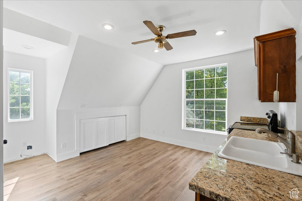 Kitchen with range, a ceiling fan, light wood finished floors, vaulted ceiling, and recessed lighting