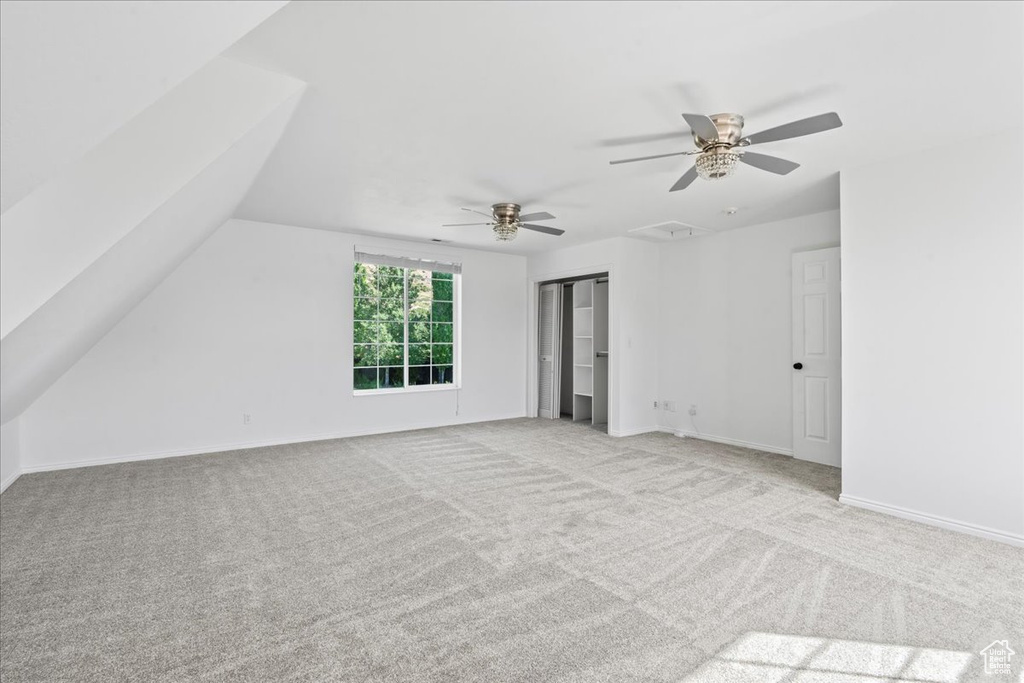 Unfurnished bedroom featuring carpet, a closet, a ceiling fan, and vaulted ceiling