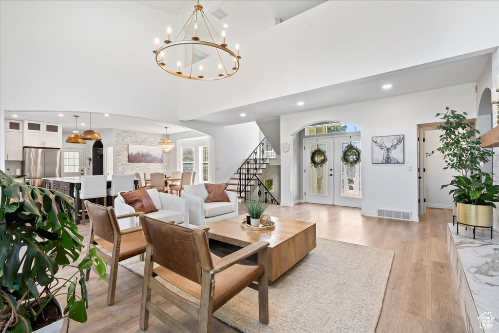 Living area featuring a chandelier, arched walkways, light wood finished floors, stairs, and recessed lighting